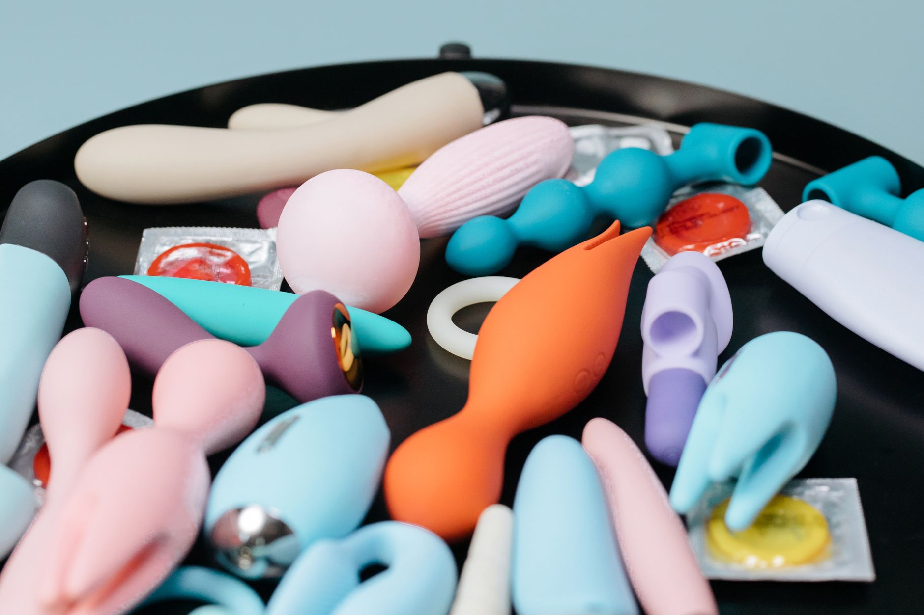 Mulher segurando vibradores de silicone azul e rosa enquanto contempla a escolha
