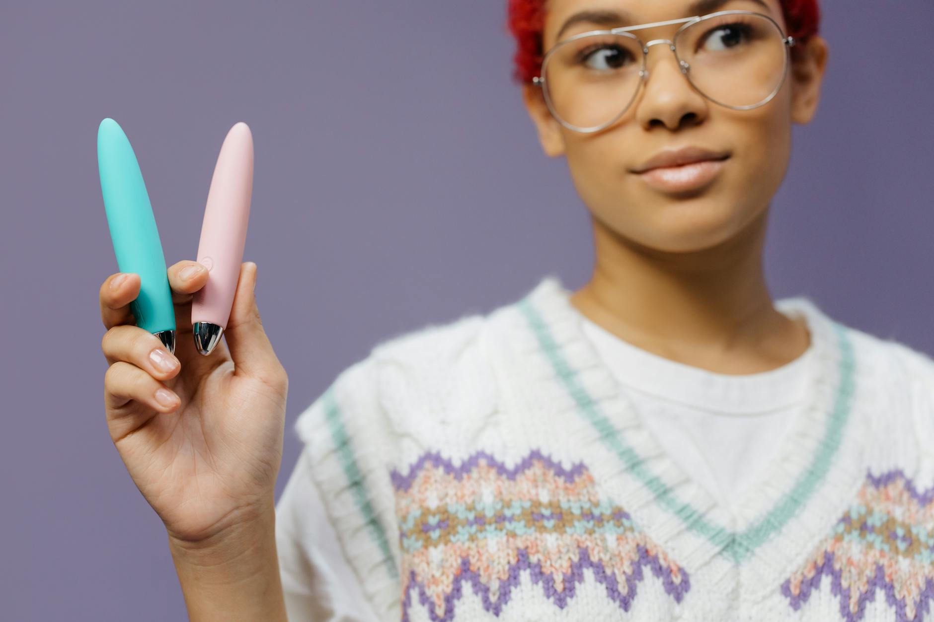 Mulher segurando vibradores coloridos contra fundo roxo