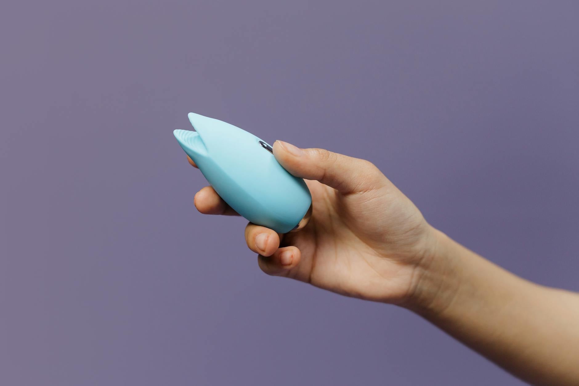 Vibrador de silicone em tons de azul sendo segurado em mão, promovendo autocuidado e sexualidade saudável